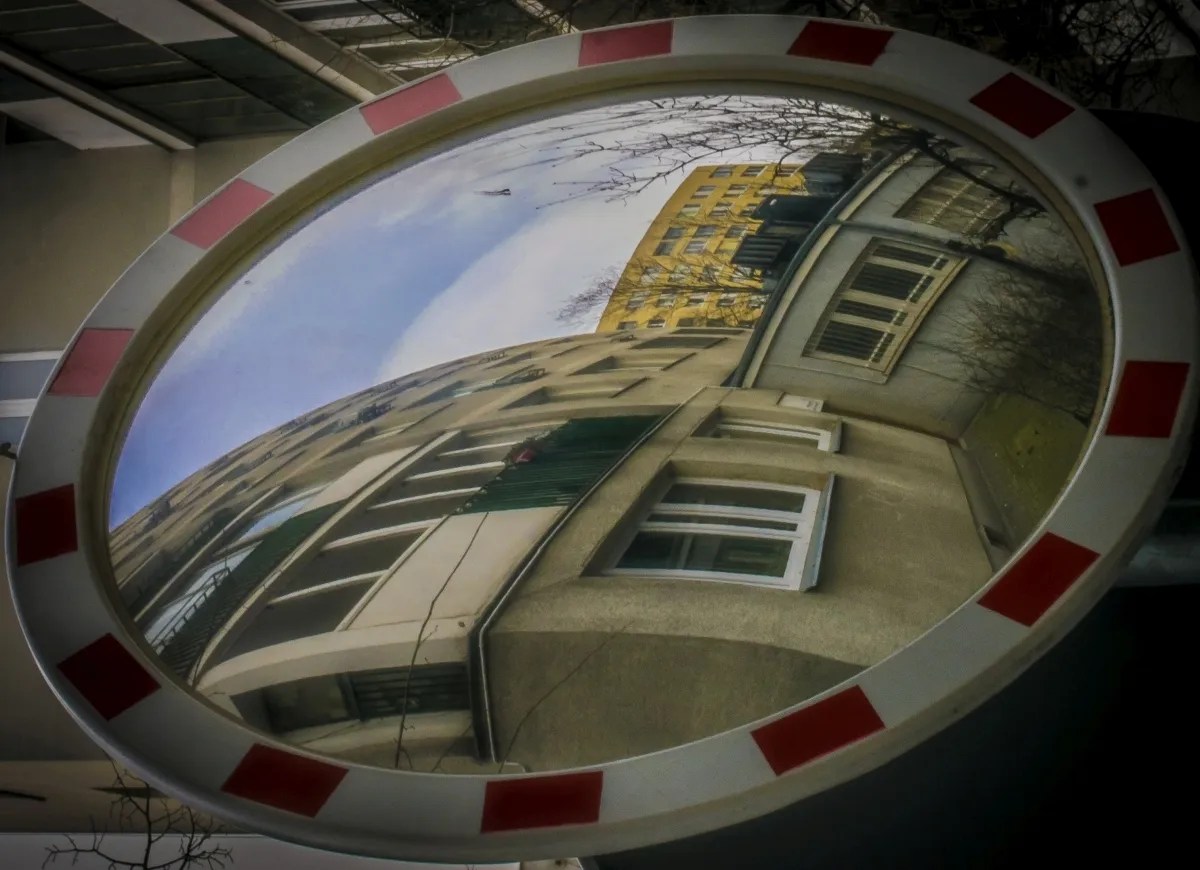 Curved building facade reflected in a round traffic mirror